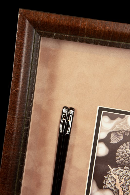 Detail of Japanese print and chopsticks in picture frame.