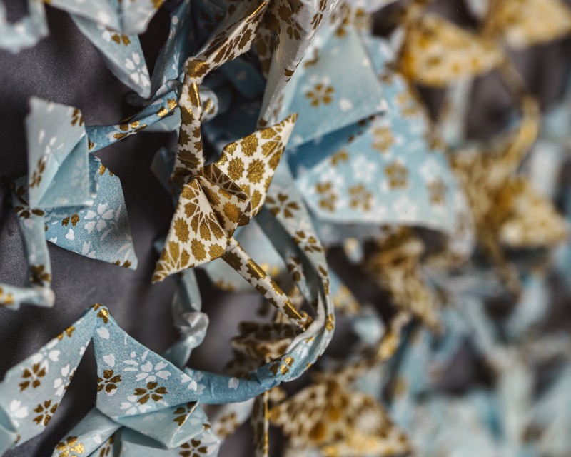 Detail of origami cranes sewn to matboard